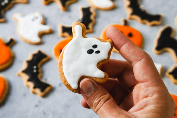 istock Hand holding ghost shaped gingerbread cookie for Halloween 2159579962