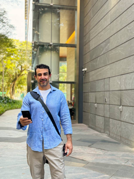 istock Mature man using cell phone on the outside of a corporate building 2159580111