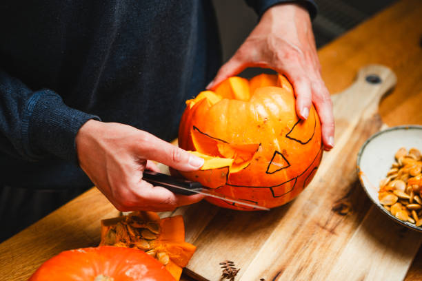 istock Man carving a pumpkin Jack O Lantern on a table for Halloween 2159582469