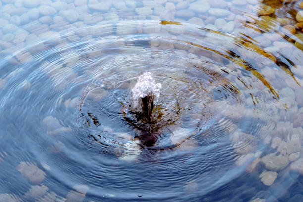 Small water fountain in a pool covered with small rocks