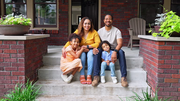 Portrait of a family with two children sitting in front of the house