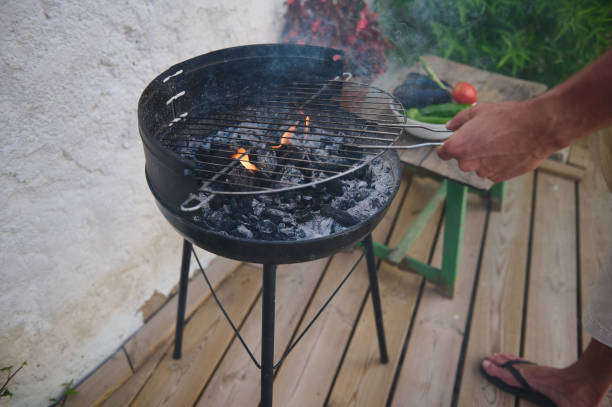 istock Man preparing a BBQ grill with charcoal on a wooden deck 2159587124