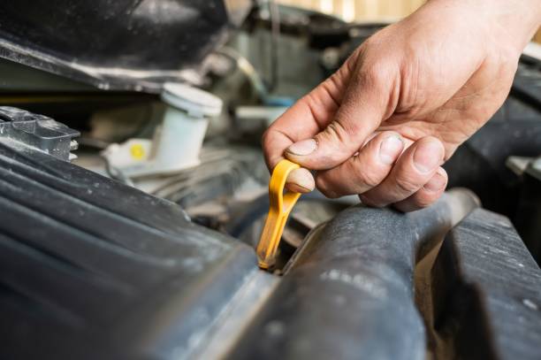 istock An auto mechanic pulls out a dipstick to check the oil level in a car engine. 2159589147