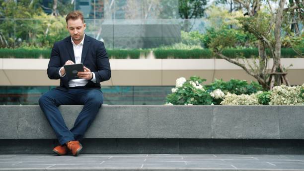 istock Smart businessman sitting while writing on tablet and planning strategy. Urbane 2159589743