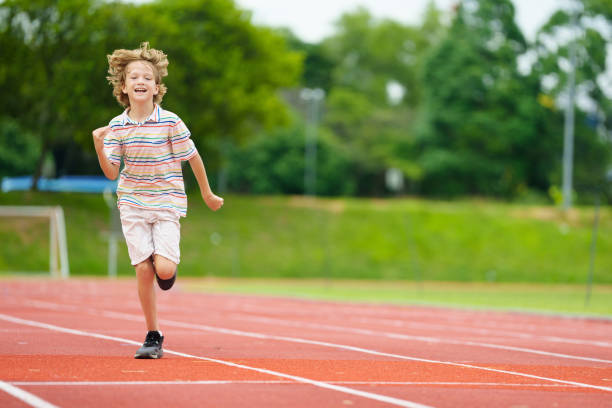 istock Child exercising. Kid running on stadium. 2159590800