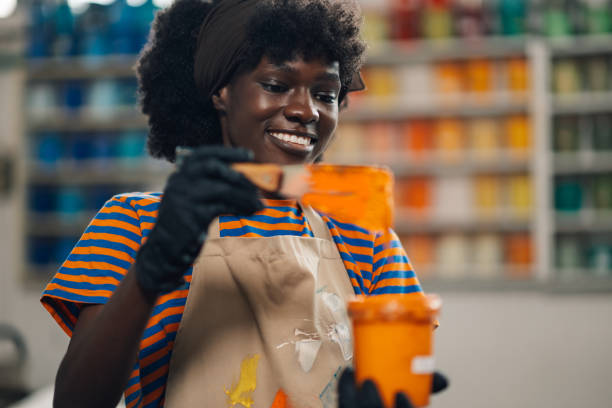 istock Portrait of diverse graphic worker mixing ink with spatula at facility 2159601197