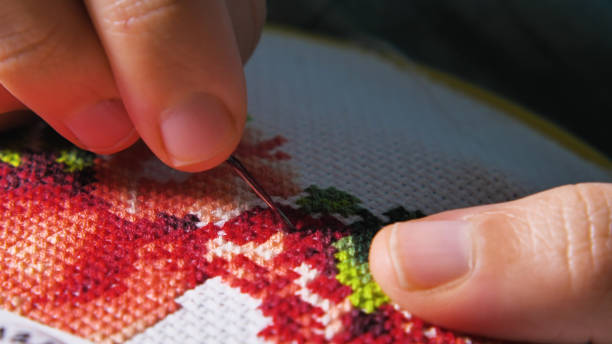 istock A close-up of hands doing cross stitch embroidery with colorful threads 2159601603