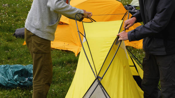 istock Two hikers putting up a yellow tent at a base camp in the mountains 2159601661