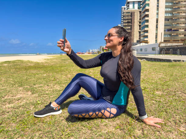 Woman on the beach after exercise, with smartphone taking selfie