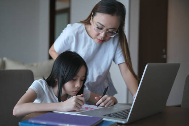 Asian Mother Watching Her Daughter Doing Homework.