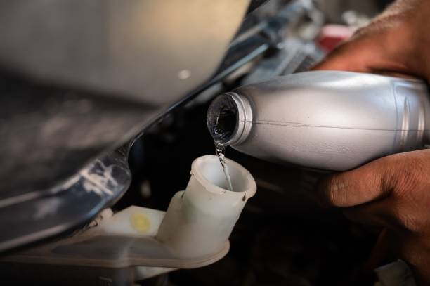 istock An auto mechanic pours brake fluid into the car 2159612648