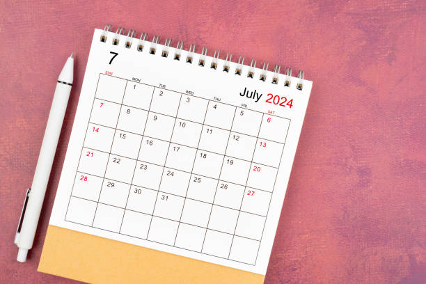 istock July 2024 desk calendar and pen on red background. 2159614555