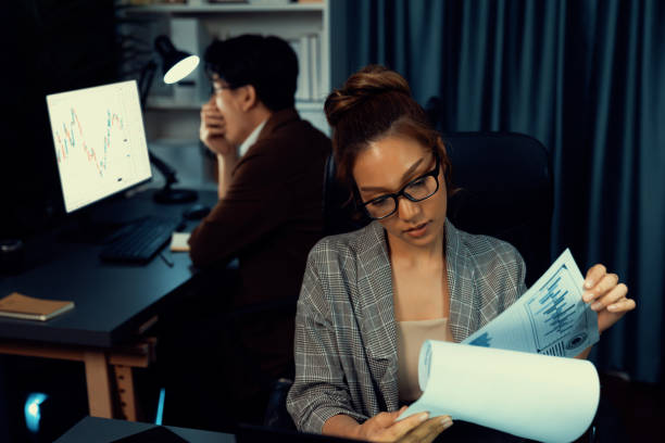 istock Businesswoman looking document paperwork while coworker trading stock. Infobahn. 2159615019