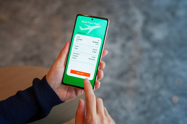 istock Over the shoulder view captures a woman using a smartphone application to book flight tickets and plan her holiday trip 2159615378
