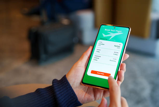 istock Over the shoulder view captures a woman using a smartphone application to book flight tickets and plan her holiday trip 2159615561