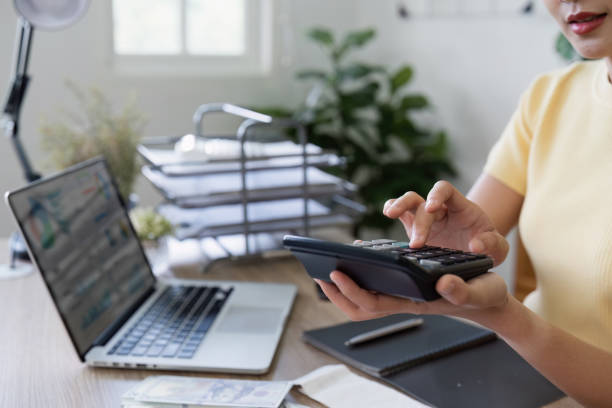 istock Woman Calculating saving with Calculator at Home Office Desk with Laptop and Documents 2159619456