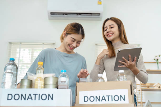 istock Two Women Organizing donate in Boxes with Labeled Signs in a Bright Room 2159619611