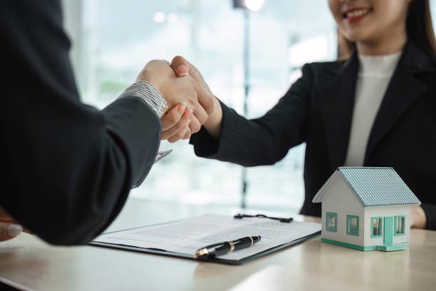 istock Real Estate Agent Shaking Hands with Client Over House Purchase Agreement in Modern Office Setting 2159621360