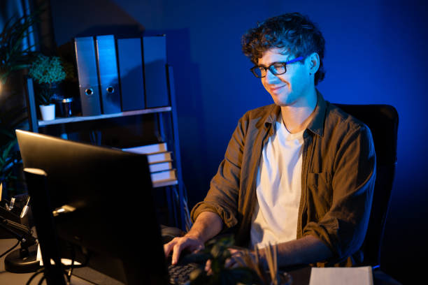 istock Smiling businessman concentrating on pc on project at neon light office. Gusher. 2159624686