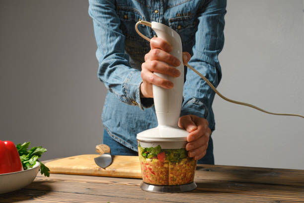Unrecognizable woman preparing salsa or guacamole in blender