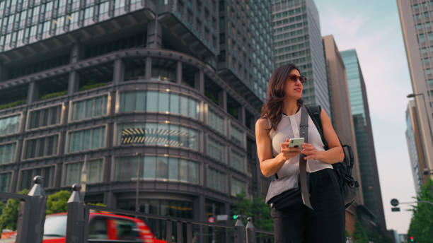 istock Beautiful woman visiting Tokyo and using her mobile smart phone to explore city 2159628437