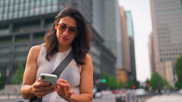 istock Beautiful woman visiting Tokyo and using her mobile smart phone to explore city 2159628488