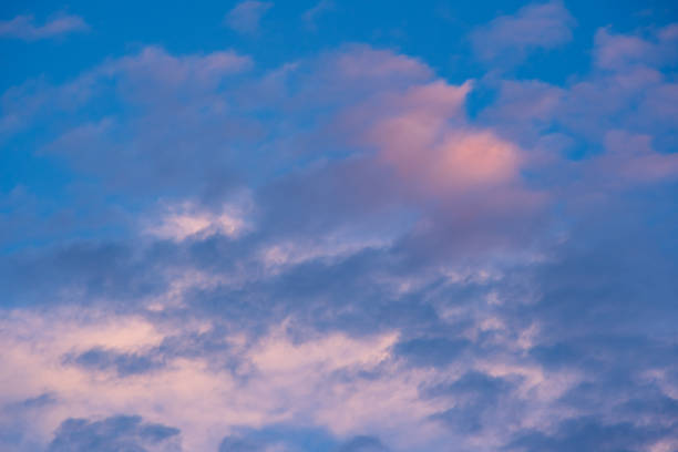 Dramatic sunset or sunrise scene. Pink and purple summer clouds against blue sky