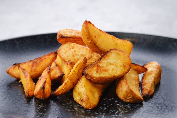 Slices of potato wedges fried in oil, closeup view Garnish to the main dish - Slices of potato wedges fried in oil, closeup view fried potato stock pictures, royalty-free photos & images