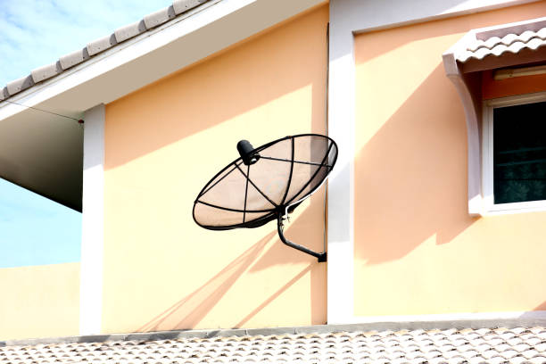 A consumer satellite television receiver dish points skyward in the middle of a forest providing satellite TV access to its owner.
