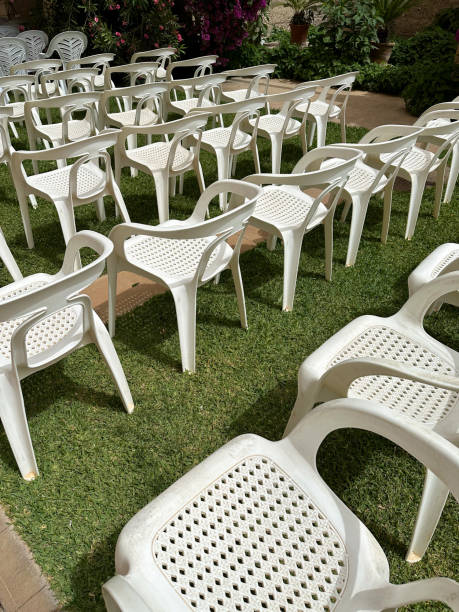 istock White plastic chairs arranged in a row on green grass outdoor 2159635889