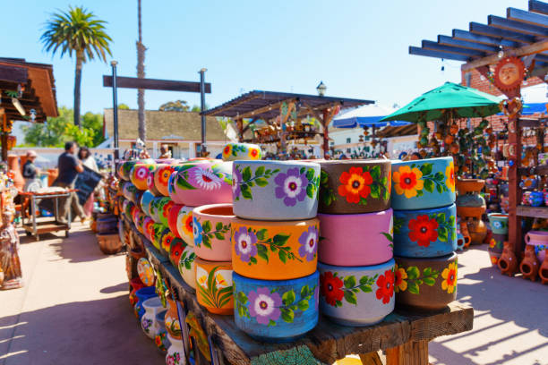 Brightly decorated Talavera pottery jars are arranged on stands at a bustling crafts market in Mexico. Each jar features intricate designs, showcasing fruits, flowers, and traditional patterns.