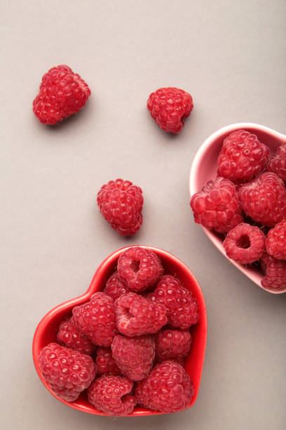 istock Fresh ripe garden raspberry in heart shaped bowl on grey background. Top view with copy space 2159637686