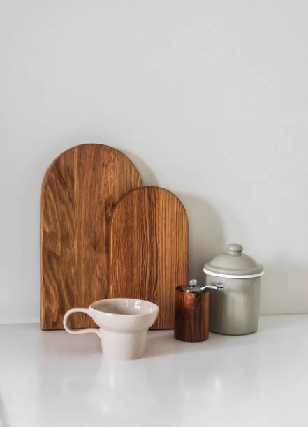 istock Minimalism style kitchen interior - wooden cutting boards, enameled container, spice mill, ceramic mug on a white surface 2159639716