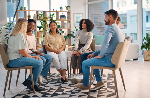 istock A diverse group of individuals attending a support group meeting, sitting in a circle in a bright, cozy room. They appear engaged and supportive as they share and listen. Ideal for concepts of community, therapy, and mental well-being. 2159641844