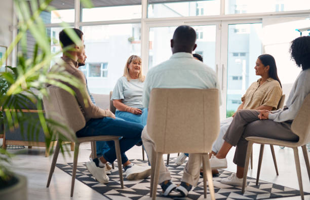 istock A diverse group of individuals sit in a circle during a support group meeting in a bright, modern room. The image conveys a sense of community, support, and understanding among participants. 2159641848