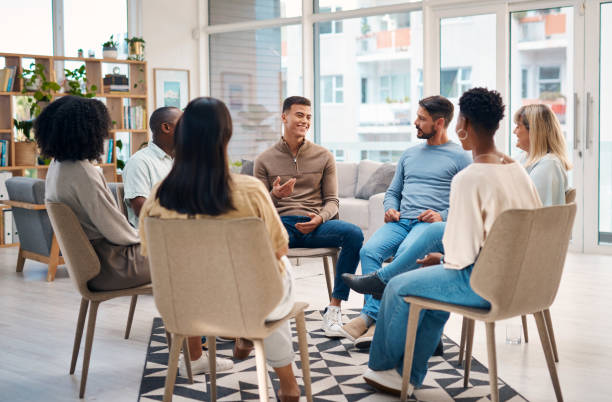 istock A diverse group of adults participating in a support group session. They are sitting in a circle and engaging in open conversation, expressing emotions and offering mutual support in a comfortable, bright room. 2159641851