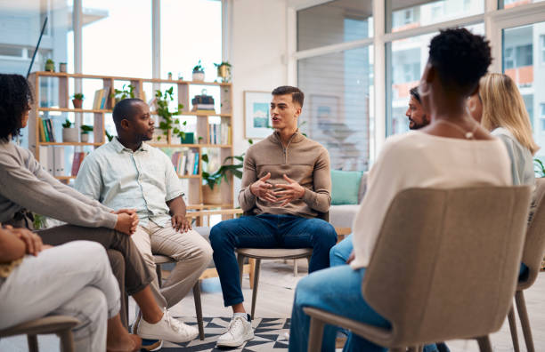 istock A diverse group of individuals engaging in a support group session, sitting in a circle in a well-lit room. They are sharing experiences and offering emotional support to one another. 2159641880