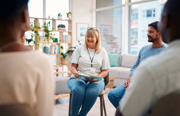 istock A diverse group of people sits in a support group circle, engaging in conversation. The setting is warm and inviting, fostering connections and emotional support. A female facilitator guides the discussion. 2159641906