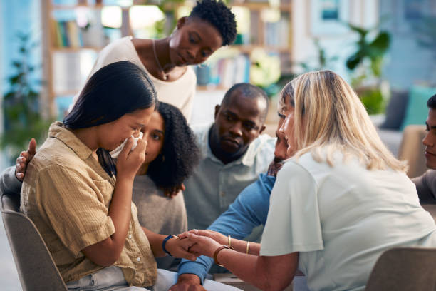 A diverse group of people attending a support group session offers emotional support to a crying woman. This touching moment captures the essence of community, empathy, and mental health awareness.