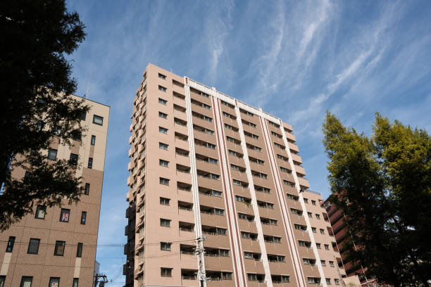 Part of a tall building with clouds and trees.