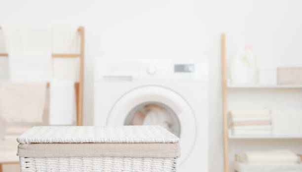 istock White closed basket in front of blurred laundry room interior background with washing machine and storage shelves 2159644471