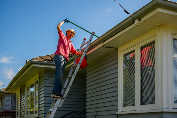 istock Man standing on the ladder and cleaning gutter with a gutter cleaning shovel. Home maintenance work. Auckland. 2159644544