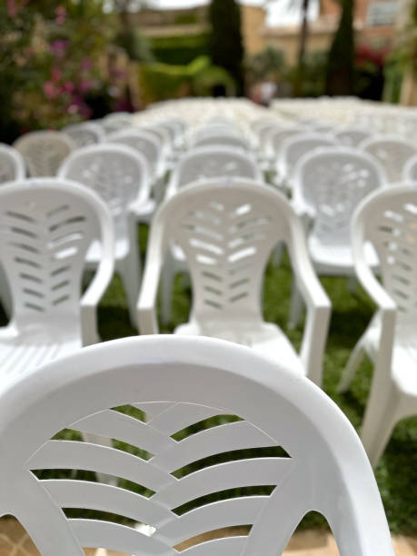 istock White plastic chairs arranged in a row on green grass outdoor 2159645455