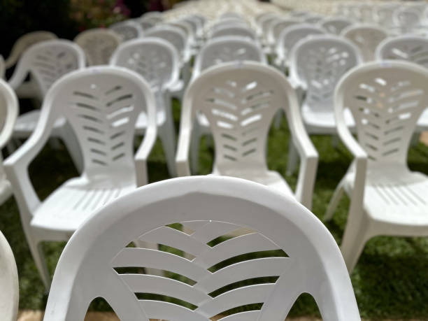 istock White plastic chairs arranged in a row on green grass outdoor 2159645513