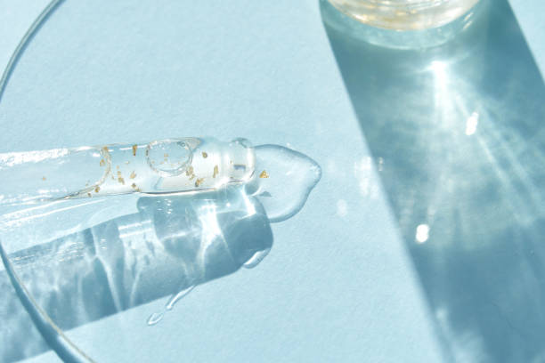 istock Serum gel texture swatch. Transparent drop golden sparkles. Blue background 2159650070