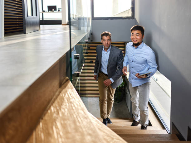 istock Happy diverse businessmen walking on staircase in a hallway. 2159650141