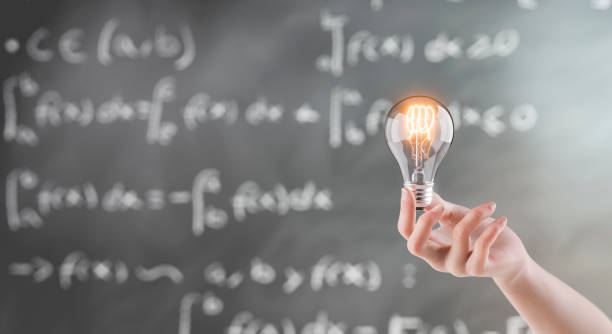 istock Hand Holding Light Bulb Against Blackboard with Mathematical Formulas 2159653905