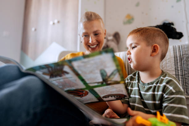 istock Mother and son reading book while sitting on a floor at home 2159656153