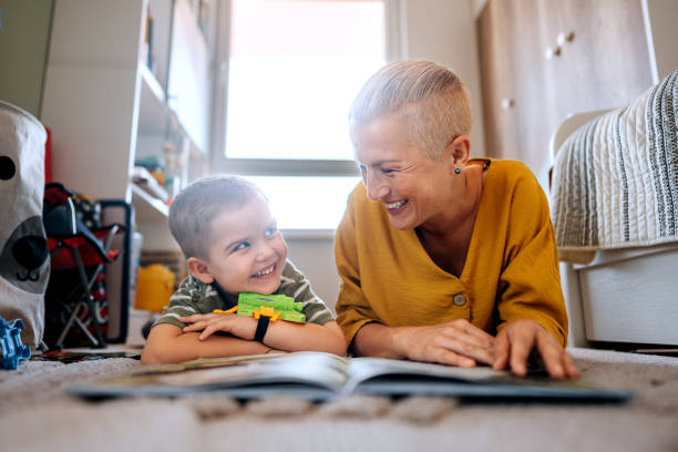 istock Mother and son reading book while laying on a floor at home 2159656154