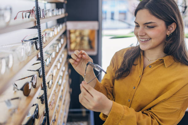 istock Smiling woman holding eyeglasses in a store 2159656486